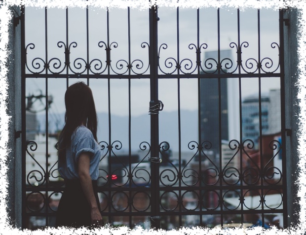 womain looking at city scape through metal gate