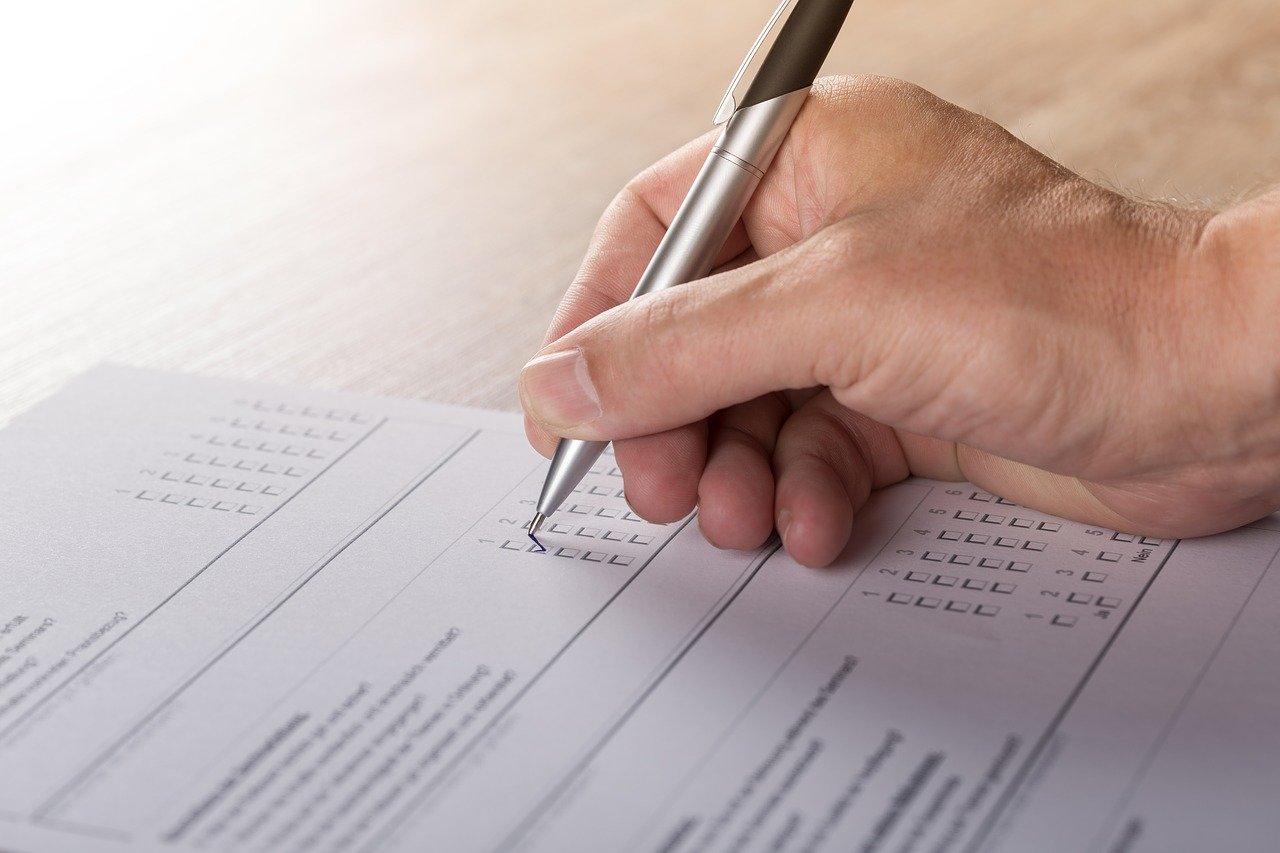 A hand using a pen to complete a survey