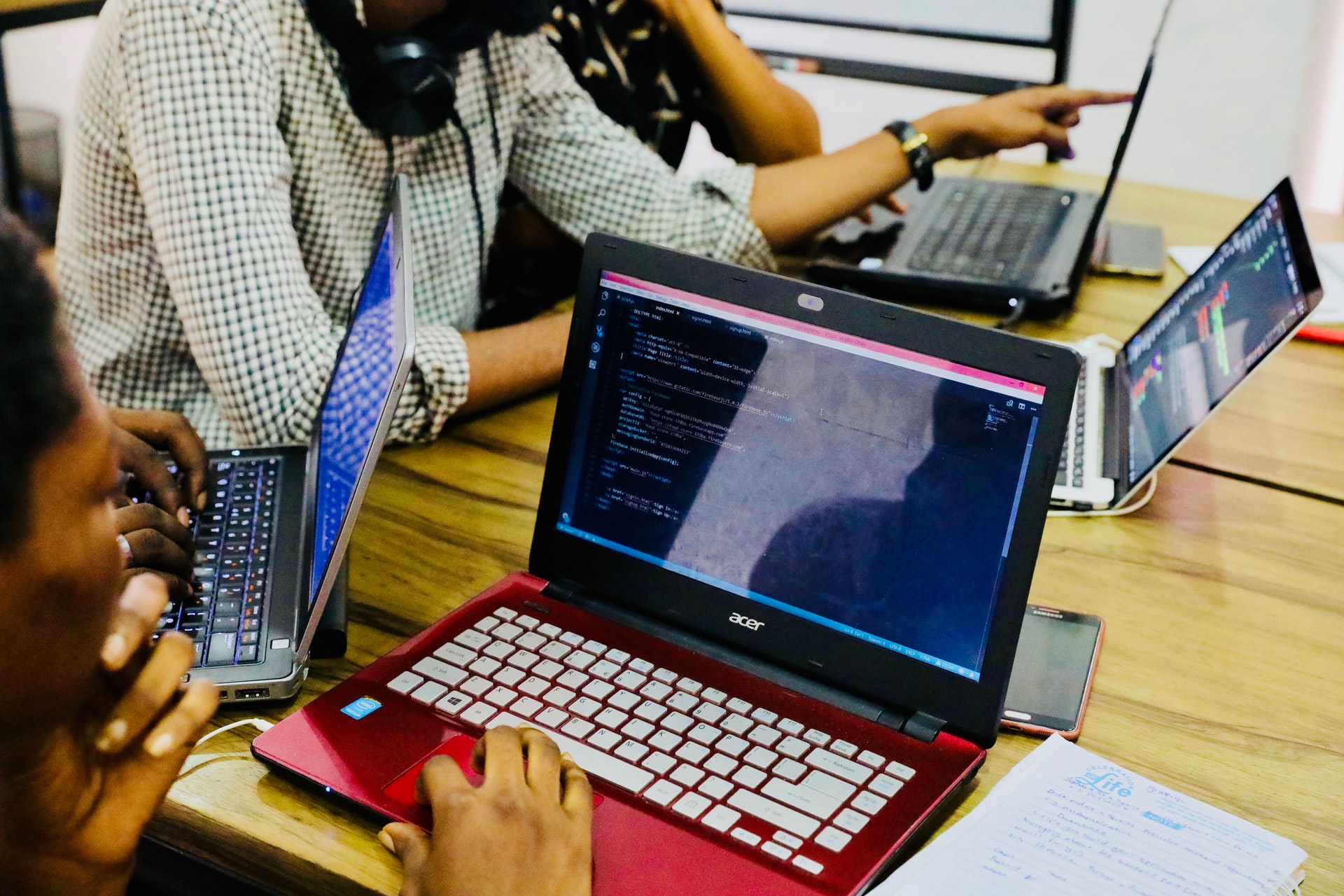 multiple individuals using laptops on a shared desk