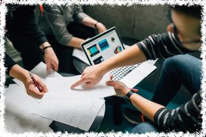 multiple individuals collaborating over a laptop and paperwork