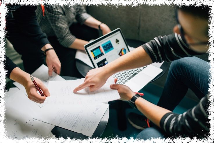 multiple individuals collaborating over a laptop and paperwork