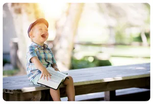 young boy reading book and laughing