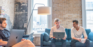 3 individuals working from laptops on a couch