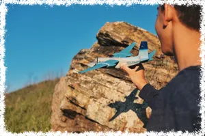 boy holding model airplane with shadow cast upon a boulder