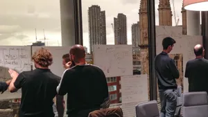 group of professionals reviewing threat model diagrams on window-cling whiteboards in a city office