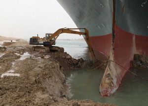 Excavator digging out sand around the box of the Ever Given in the Suez Canal, March 2021